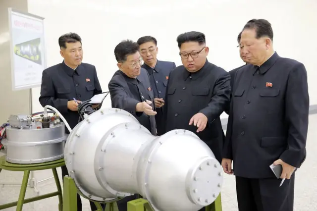 Kim Jong Un, rodeado de cinco funcionarios norcoreanos observan el revestimiento metálico de lo que aparenta ser una bomba