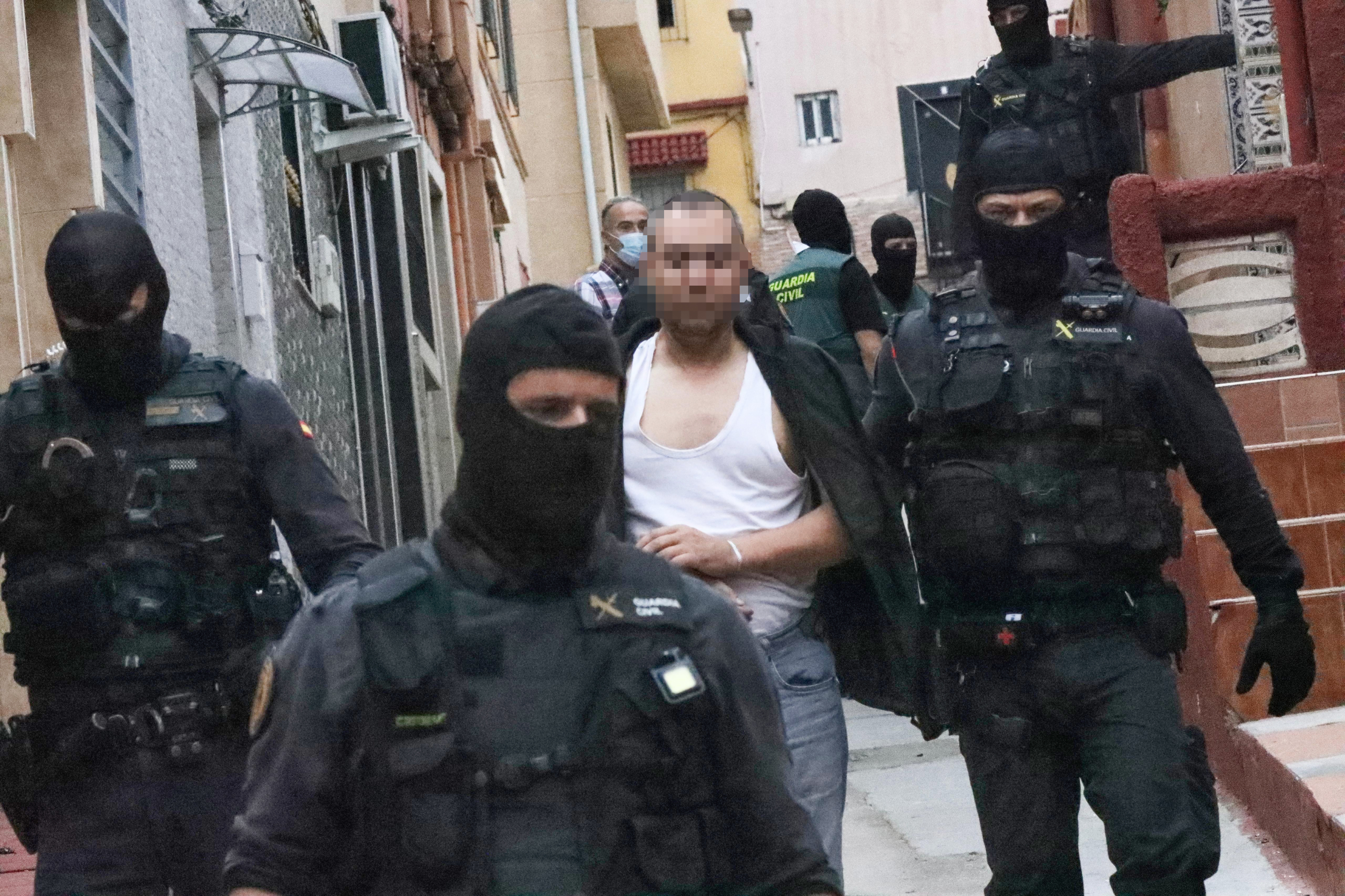 Agentes de la Guardia Civil se llevan a un detenido en la operación en Ceuta.