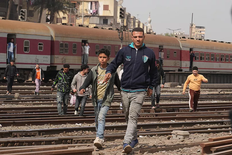 Passengers egipcios cruzan el ferrocarril en un barrio popular de El Cairo, 13 de marzo de 2025