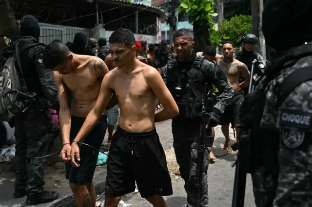 Agentes de policía escoltan a presuntos delincuentes arrestados durante la Operación Contención en la favela Vila Cruzeiro, en el complejo Penha, Río de Janeiro, Brasil, el 28 de octubre de 2025.