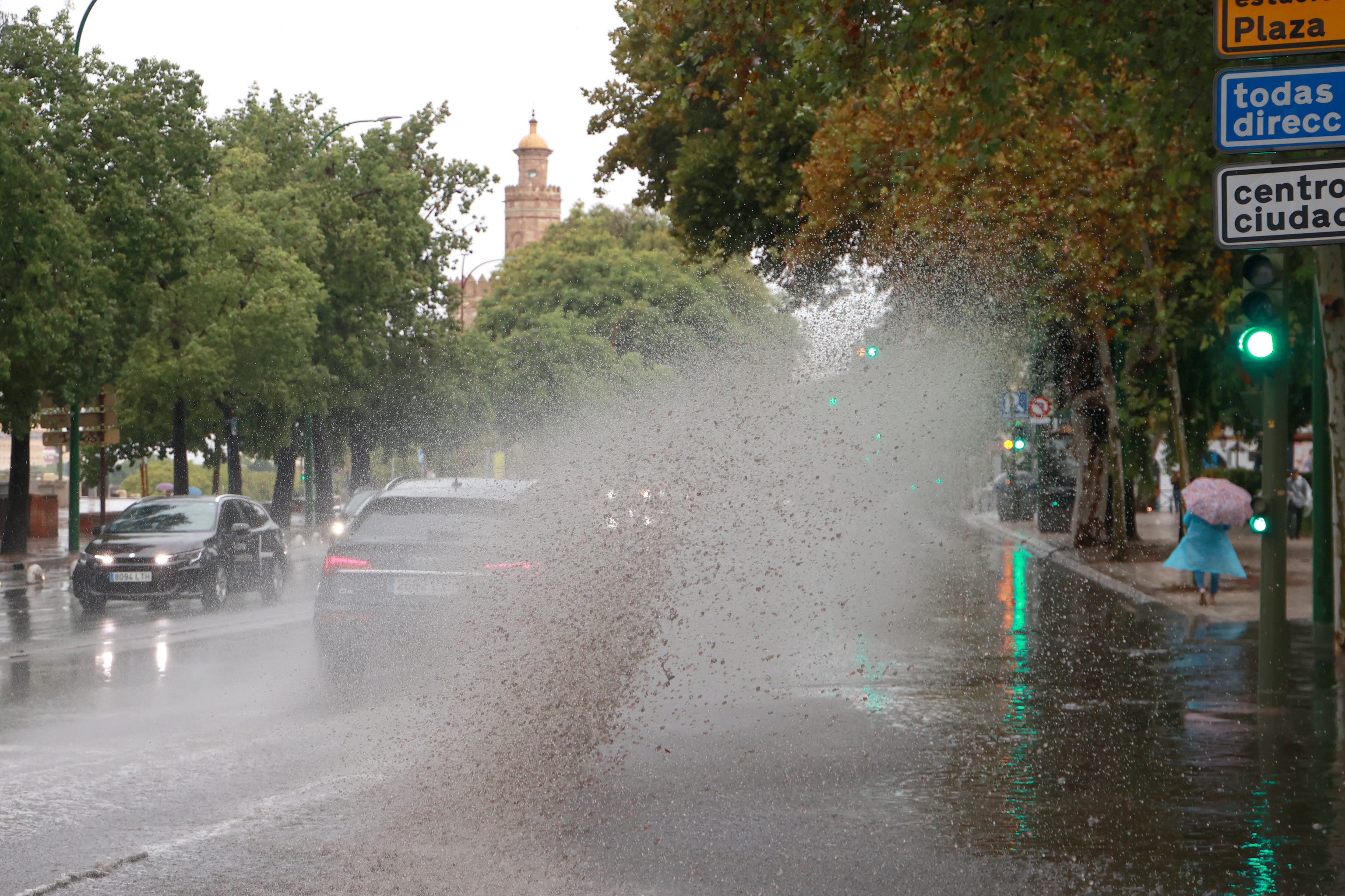 Un coche circula por una calle empapada por la lluvia en Sevilla.