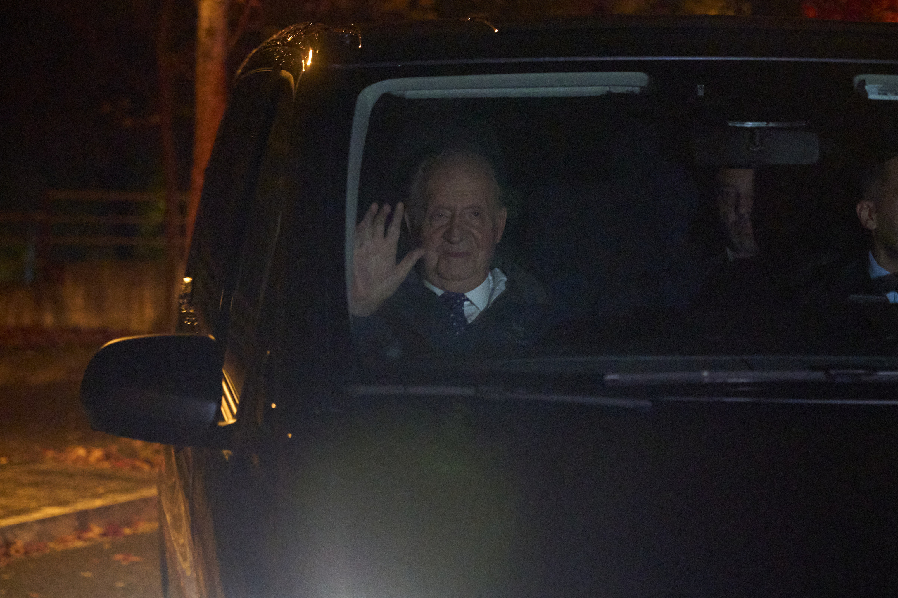 El rey Juan Carlos saluda desde el coche esta noche de miércoles en Vitoria donde acude a una revisión médica con el doctor Eduardo Anitua antes de continuar su viaje a la localidad portuguesa de Cascais.