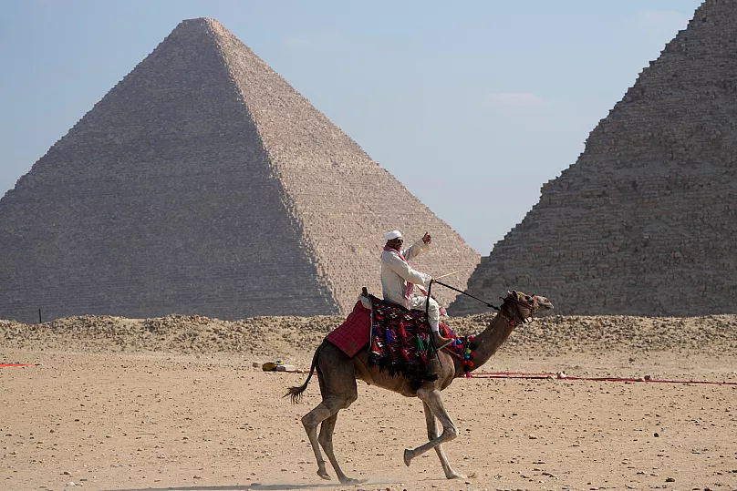 Un guía turístico monta un camello en el sitio histórico de las Pirámides de Giza, 29 octubre 2024