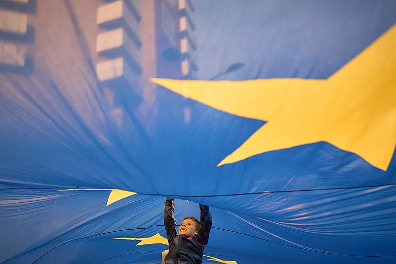 A child jumps under an EU flag during a rally in Bucharest, 9 May, 2025