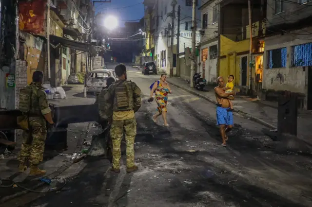 Los residentes pasan junto a los agentes de policía durante un operativo en el Complexo do Alemão.