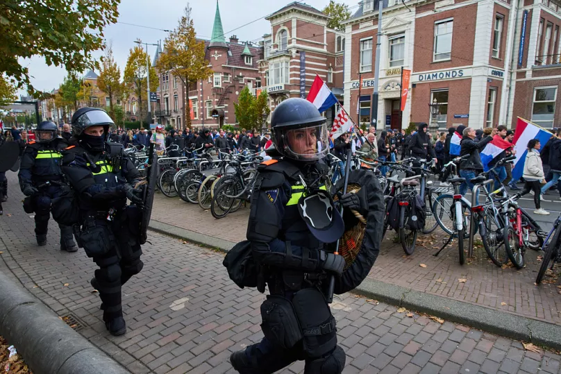 Dutch riot police escort anti-immigration protesters during a demonstration in Amsterdam, Netherlands, 12 October 2025