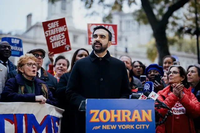 Zohran Mamdani habla en un acto de campaña rodeado de simpatizantes. 