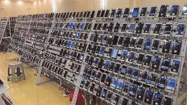 Una sala llena de estantes que contienen cientos de teléfonos móviles, cada uno conectado a una fuente de energía.