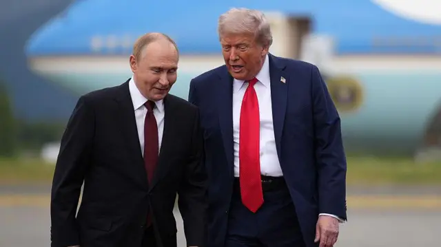 Putin y Trump caminan por la alfombra roja, charlando amigablemente con la parte delantera del Air Force One al fondo.