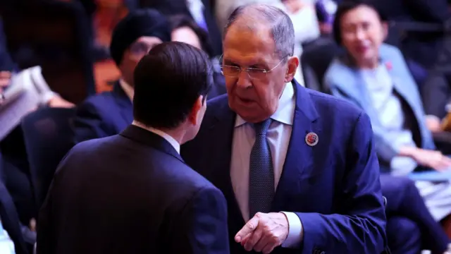 El ministro de Asuntos Exteriores de Rusia, Sergei Lavrov, frente a Rubio con la mano extendida hacia él, durante la XV Reunión de Ministros de Asuntos Exteriores de la Cumbre de Asia Oriental celebrada en el Centro de Convenciones de Kuala Lumpur, capital de Malasia, el 11 de julio de 2025. Otros delegados están sentados detrás de ellos.