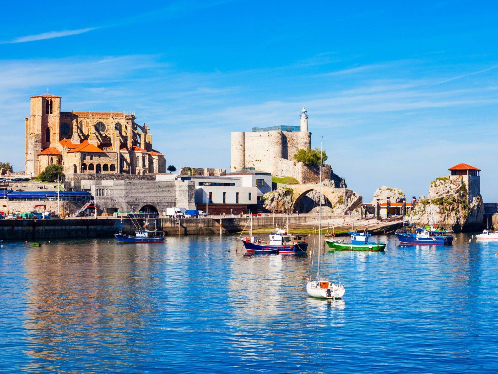 Foto: Vista de un pintoresco puerto del norte de España, con una imponente iglesia gótica y un antiguo castillo vigilando el mar Cantábrico. (Turismo Cantabria)