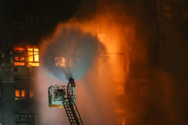 Un brazo mecánico de bomberos arroja agua sobre varios pisos incendiados en un edificio de Hong Kong