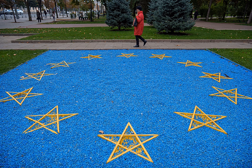FILE - A woman walks by a depiction of the European Union flag near a park in central Chisinau, 17 October 2024