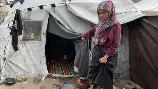 Fatima junto a su carpa. El agua sucia llega hasta la entrada de la carpa.