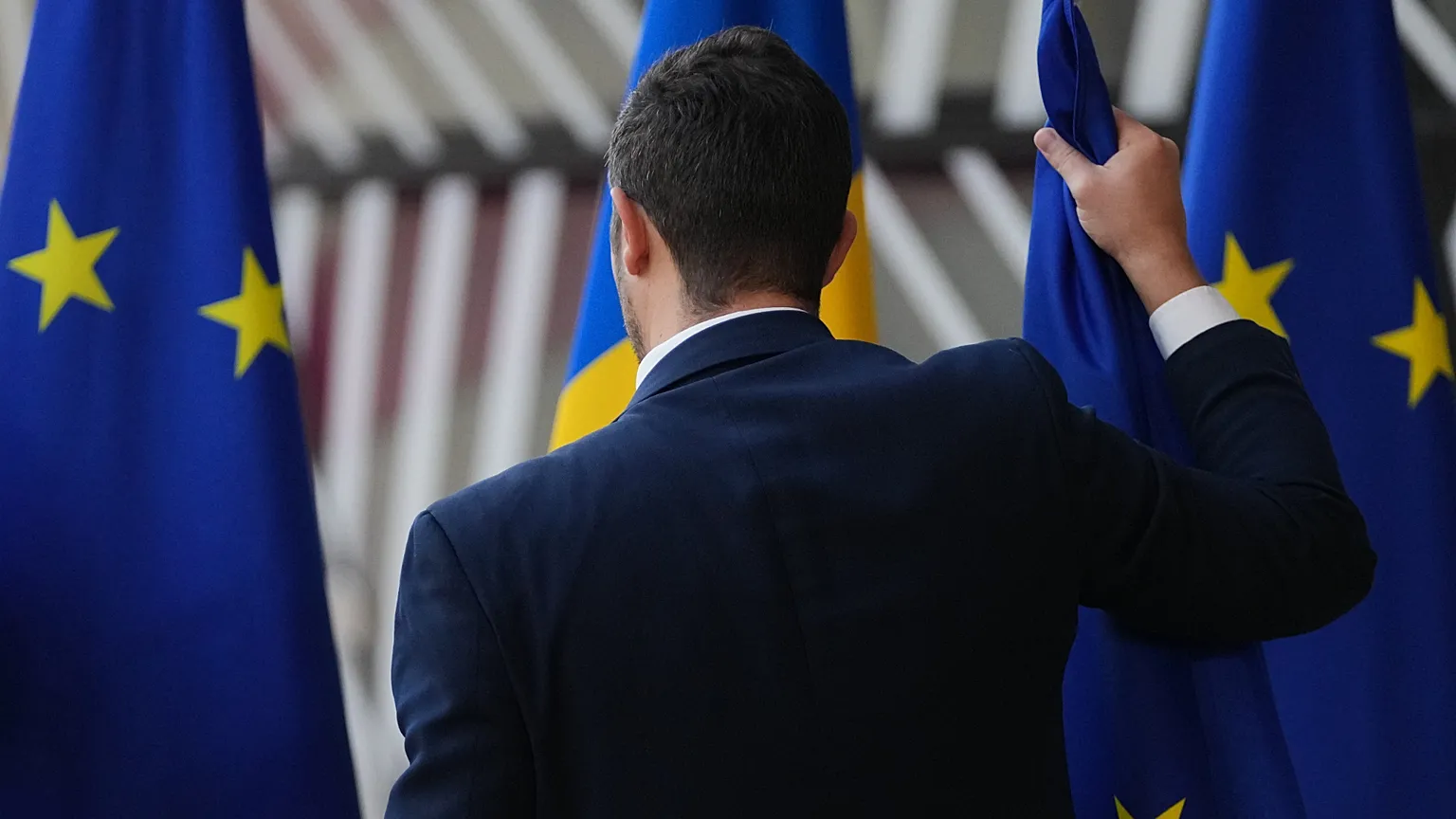 A member of protocol swaps out EU flags prior to the arrival of Moldova's President Maia Sandu at the European Council building in Brussels, 4 November 2025