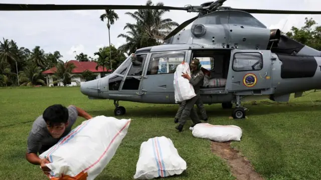 Un hombre joven carga un saco de asistencia desde un helicóptero
