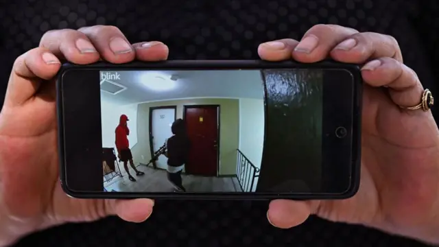 Cindy Romero sostiene su celular con el video de vigilancia que publicó, que supuestamente muestra a miembros armados de la pandilla Tren de Aragua en su antiguo edificio de apartamentos en Aurora, Colorado, el 28 de octubre de 2024.