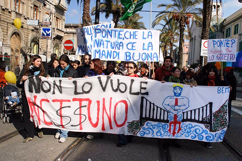 FILE- Demonstrators in Messina, Sicily, carry a sign reading “Nobody Wants It” during a protest against the planned bridge to mainland Italy, Sunday, Jan. 22, 2006.
