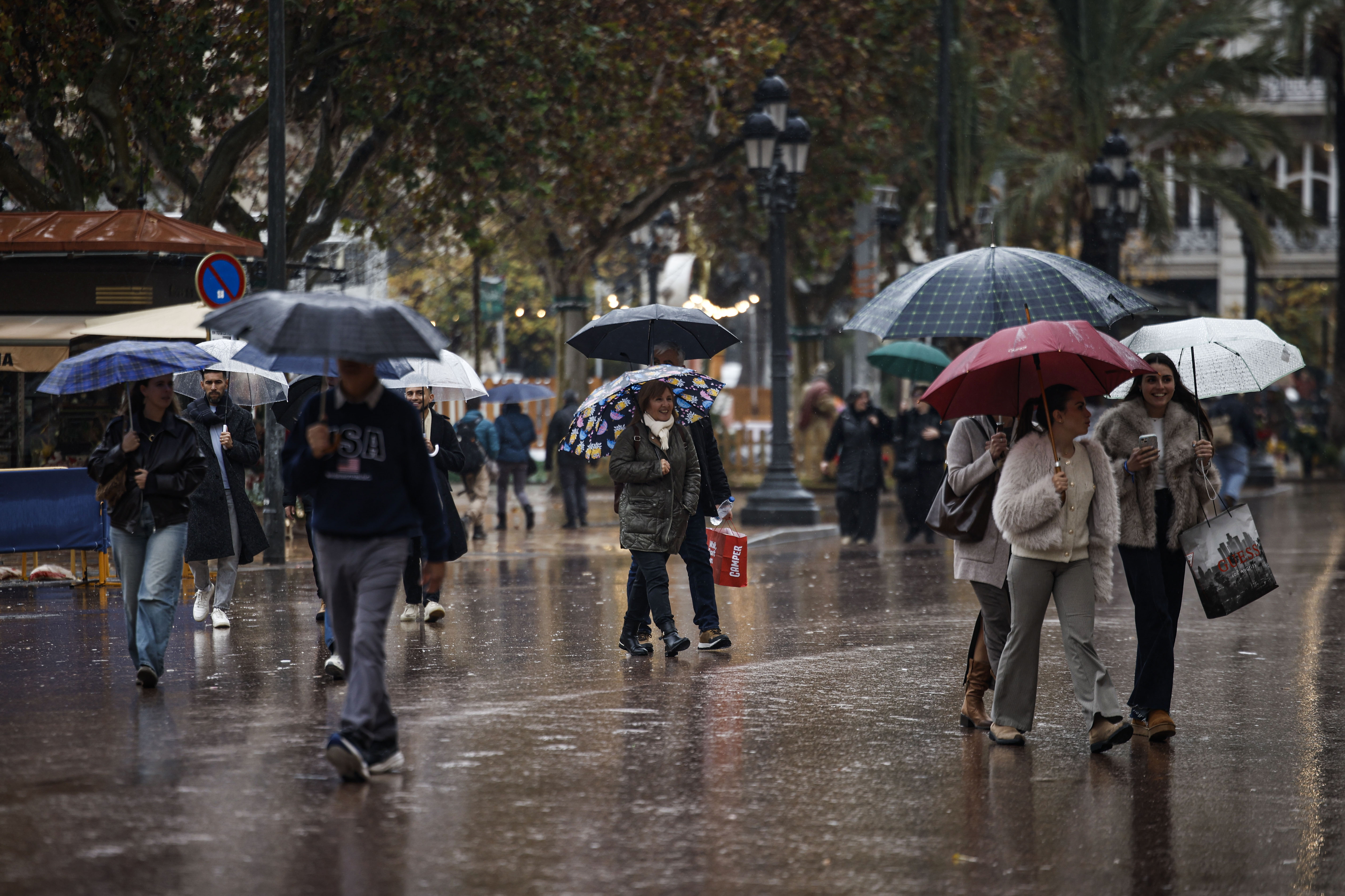 Varias personas caminan por Valencia con sus paragüas.