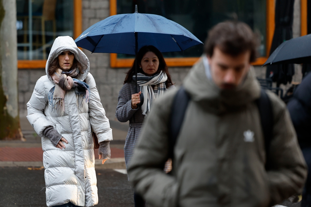 Varios transeúntes se protegen de
