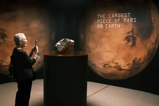 Una mujer fotografía el meteorito que fue subastado por Sotheby's por más de US$ 4 millones.