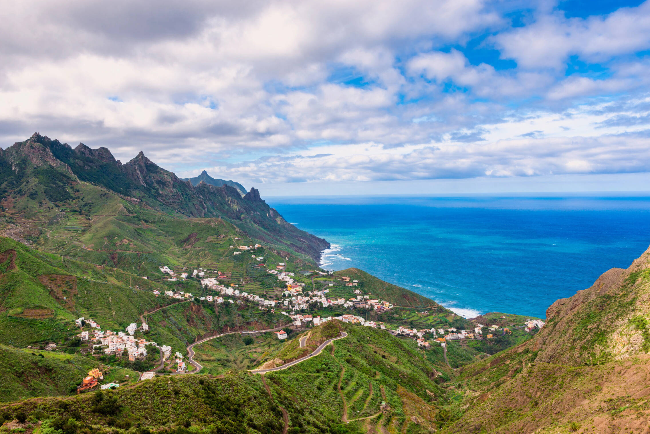 Foto: Entre barrancos verdes y el azul profundo del Atlántico, un caserío de Tenerife se descuelga por la ladera. (expedia.es)