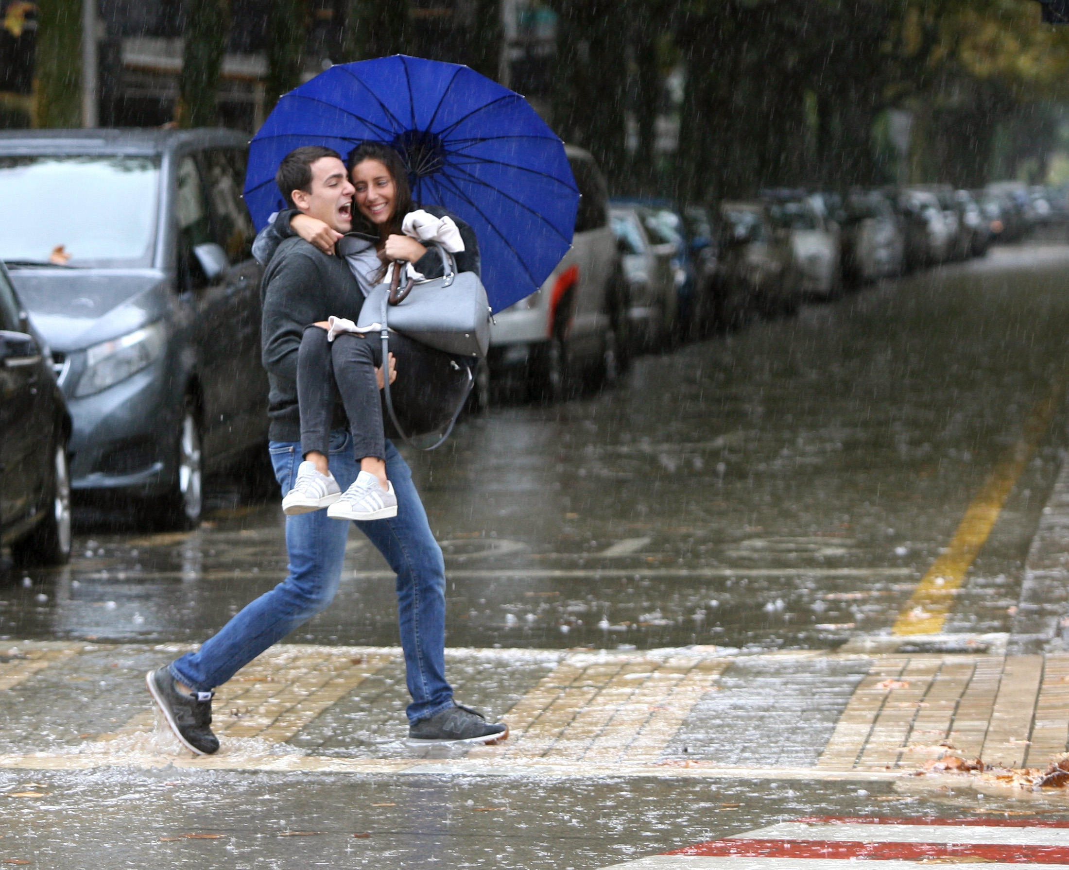 Una pareja cruza una calle de Salou casi inundada por la lluvia.