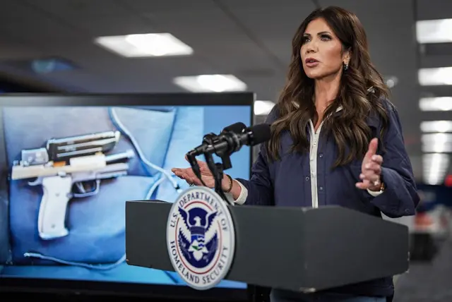 La secretaria de Seguridad Nacional, Kristi Noem, exhibe el arma que supuestamente llevaba la víctima.