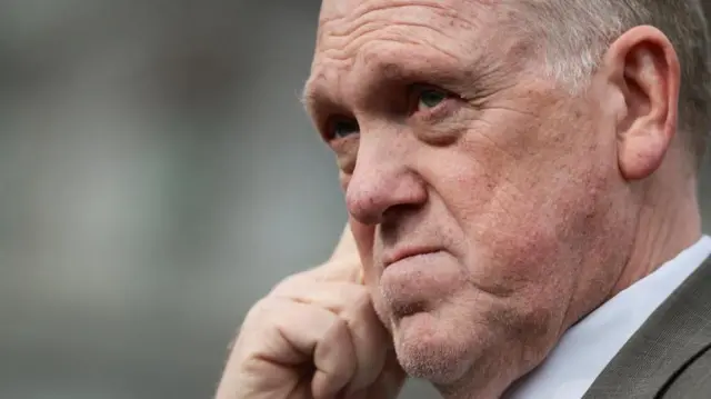 Tom Homan, el zar fronterizo de Trump, aparece pensativo mientras se lleva la mano a la cara y mira fijamente a lo lejos en una foto tomada en primer plano en los terrenos de la Casa Blanca.