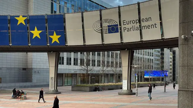Vista exterior de uno de los edificios del complejo de Parlamento Europeo. Un gran rótulo muestra los colores y las estrellas de la bandera europea y el nombre de la institución.