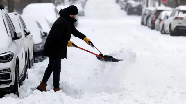 Un hombre usa una herramienta para limpiar la nieve acumulada por la termoneta invernal