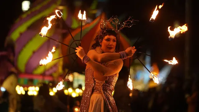 Una artista callejera participa en la Procesión de la Luz en Dublín. Sostiene un artefacto con fuego en el extremo.