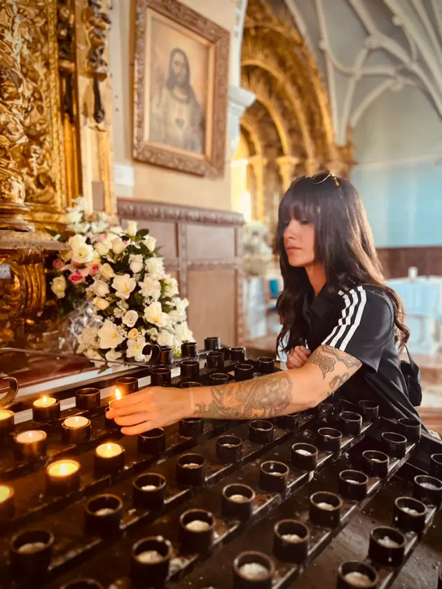 Anaí Meléndez enciende una vela en una iglesia.
