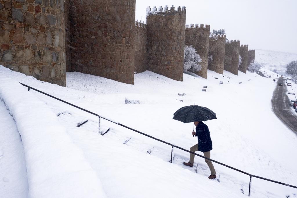 Un hombre camina junto a la muralla de Ávila.