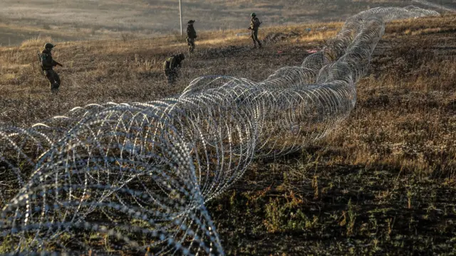 Unos soldados ucranianos instalan alambres y otras defensas contra tanques