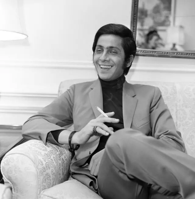 Valentino en su juventud, sentado en un sillón con un cigarrillo en la mano