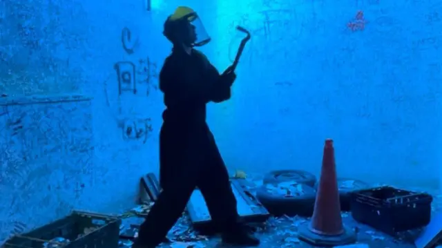Imagen de alguien en una sala de ira rodeado de objetos para destruir.