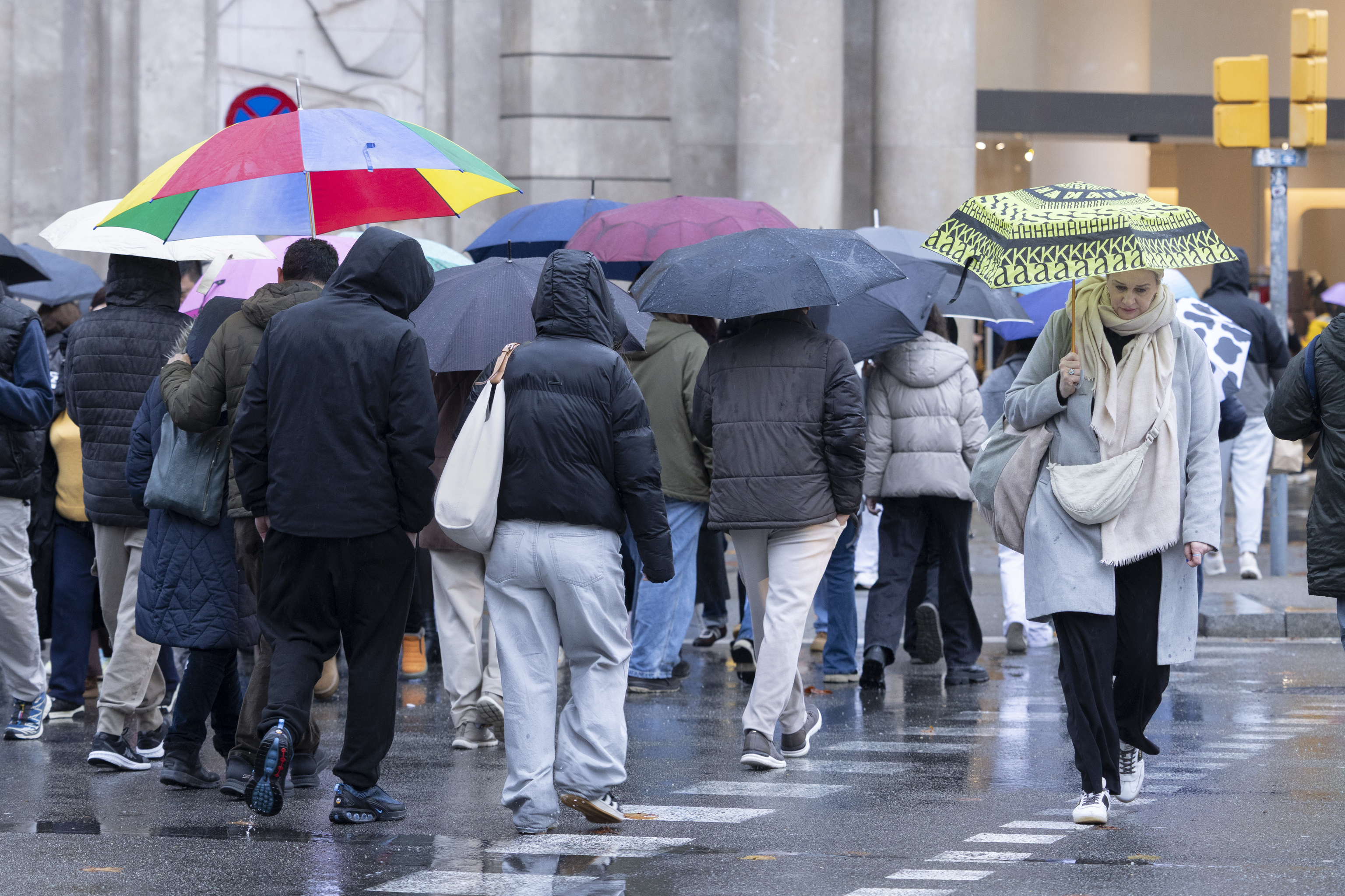 Varias personas caminan bajo la lluvia en Barcelona.