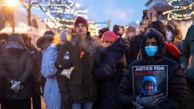 Un grupo de personas congregadas en el lugar donde murió Alex Pretti. Uno muestra un cartel que pide "justicia para Alex Pretti".
