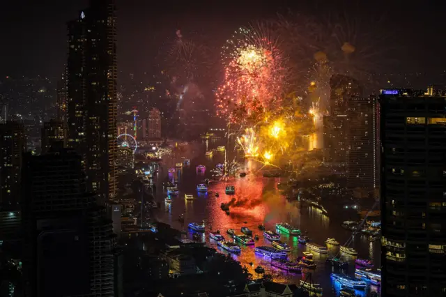 Fuegos artificiales sobre el río Chao Phraya en Bangkok, Tailandia, iluminando el horizonte y los barcos.