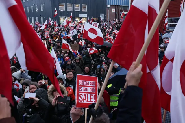 Unos manifestantes con banderas de Groenlandia y una pancarta con el mensaje "Groenlandia no está en venta" en inglés, en una protesta contra los planes de Trump en Nuuk.