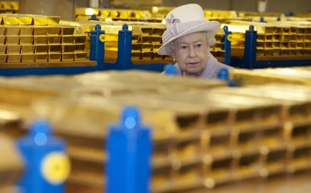 La fallecida Isabel II pasea por entre los lingotes de oro que están en el Banco de Inglaterra.