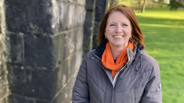Harriet Eaton, funcionaria de Educación Patrimonial del consejo de Neath Port Talbot, parada en el parque en Margam vestida con un abrigo gris y bufanda naranja