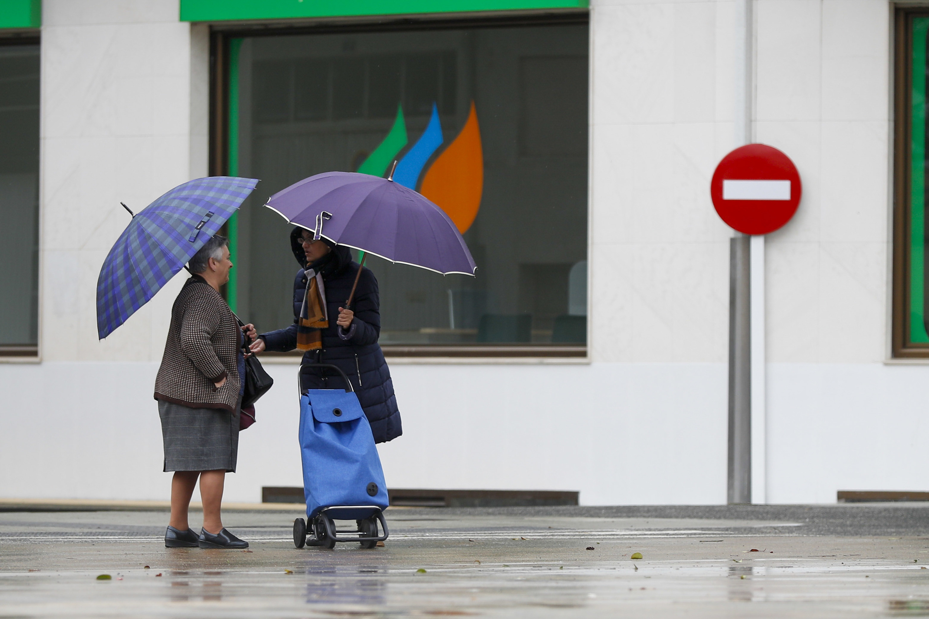 Dos mujeres se protegen con paraguas de la lluvia en Melide (A Coruña).
