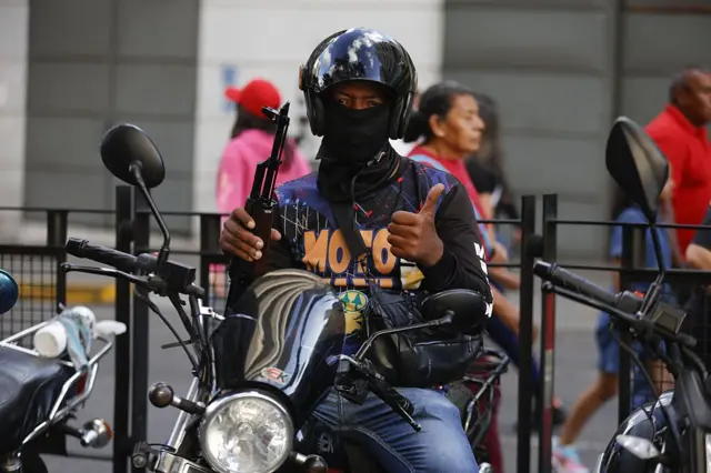 Un miembro de un colectivo chavista en una moto, con un fusil.
