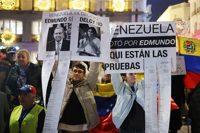 Manifestantes sostienen carteles en apoyo del líder opositor venezolano Edmundo González Urrutia y en contra de la presidenta interina de Venezuela, Delcy Rodríguez, durante una manifestación para exigir libertad para Venezuela, tras la operación militar estadounidense en Venezuela para capturar al presidente venezolano, en Madrid el 4 de enero de 2026.
