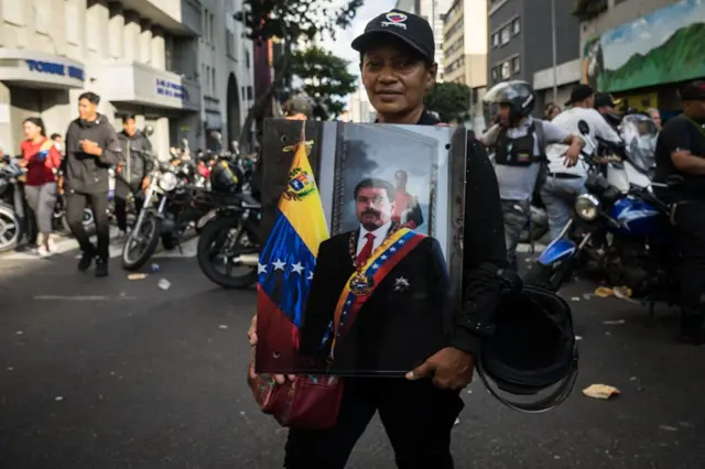 Una simpatizante chavista sostiene en sus brazos un retrato de Maduro con la banda presidencial.