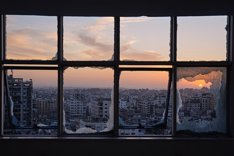 The sun sets behind war-damaged buildings in Gaza City, 31 December 2025