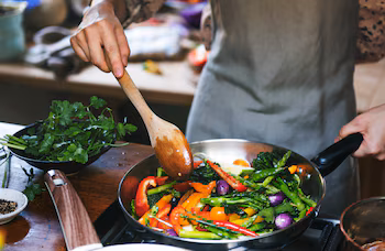 Un hombre cocinando verduras en