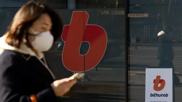 Un transeúnte camina frente a un centro de atención al cliente de Bithumb.